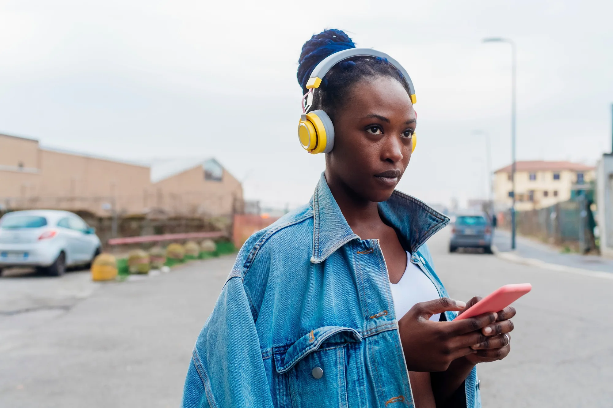 Italy, Milan, Woman with headphones holding smart phone in city